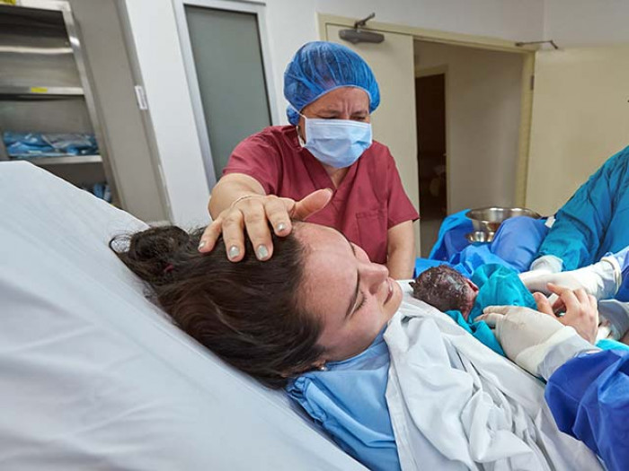 Mum holding new baby after O&G doc helped deliver